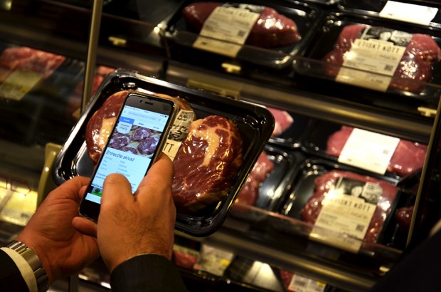 mobil hålls upp framför ett paket kött