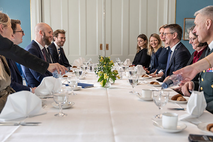 De svenska representanterna och de danska sitter vid ett avlångt dukat bord för en lunch.