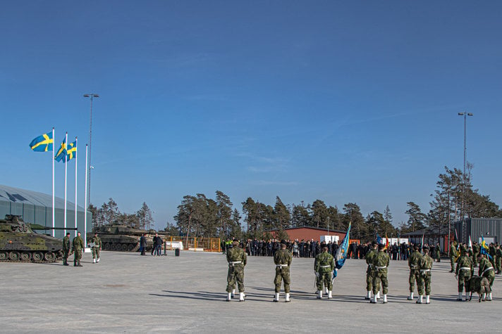 Ceremoni utomhus under blå himmel med en stor grupp soldater.