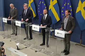 Fyra personer avbildade snett uppifrån står vid var sin talarpulpet.