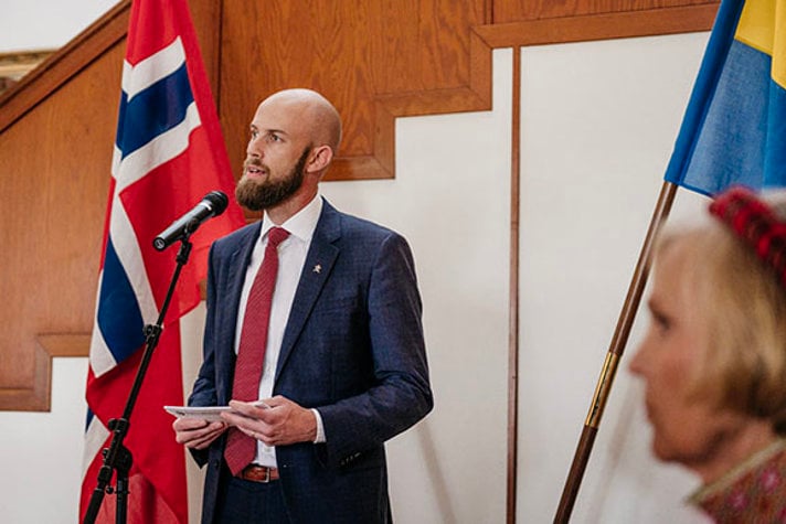 Minister för civilt försvar Carl-Oskar Bohlin håller tal. I bakgrunden syns den norska och svenska flaggan. 