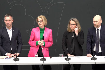 De medverkande står bakom ett långbord med mikrofoner på