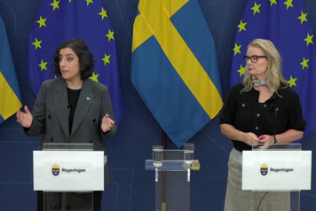 utbildnings- och integrationsminister Simona Mohamsson och gymnasie-, högskole-, och forskningsminister Lotta Edholm vid var sin talarstol med flaggor i fonden.