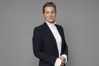 Karin Juhlin framför grå bakgrund.