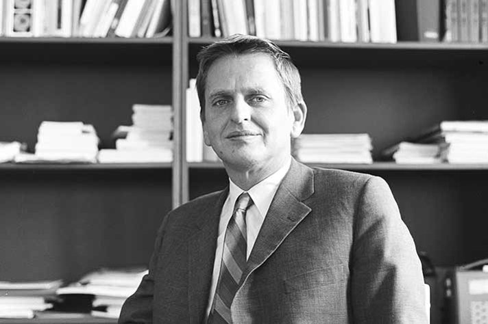 Olof Palme framför en bokhylla.