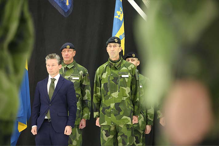 Försvarsminister Pål Jonson och överbefälhavare Micael Bydén står bredvid varandra, framför två män i uniform, vid invigningen av återetableringen av Bergslagens artilleriregemente A 9.