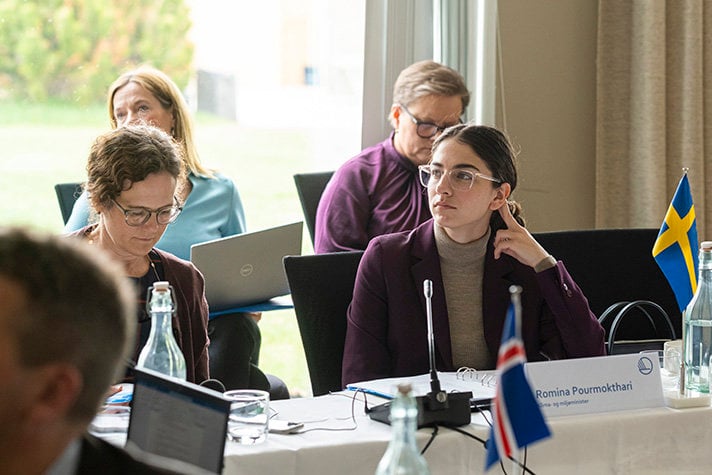 Klimat- och miljöminister Romina Pourmokhtari lyssnar på sina kollegor runt ett bord