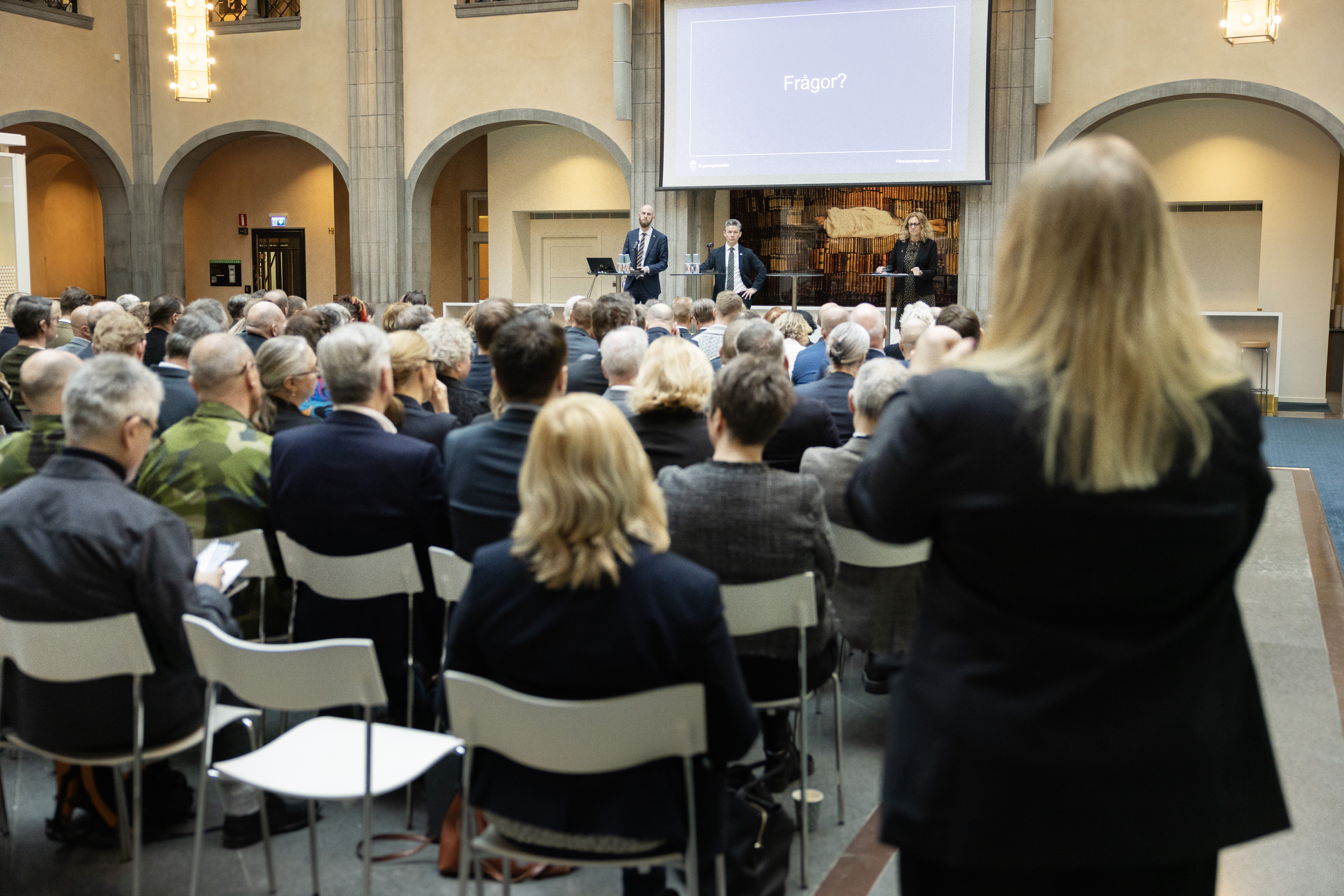 Ministrarna i kostym framför ett folkhav.