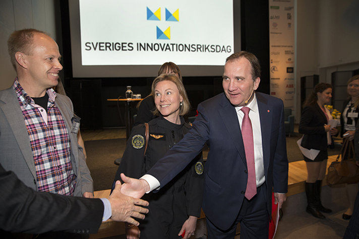 Stefan Löfven skakar hand med deltagare.