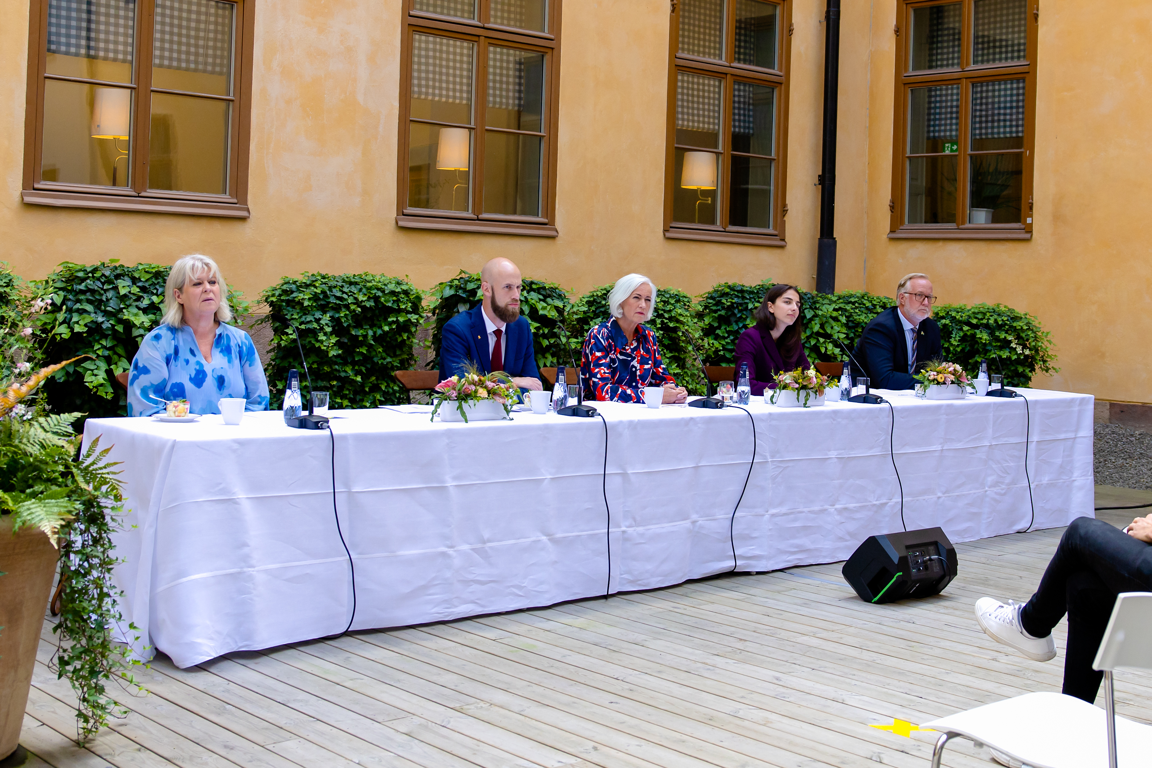 Statsråden sittande på rad bakom ett bord.