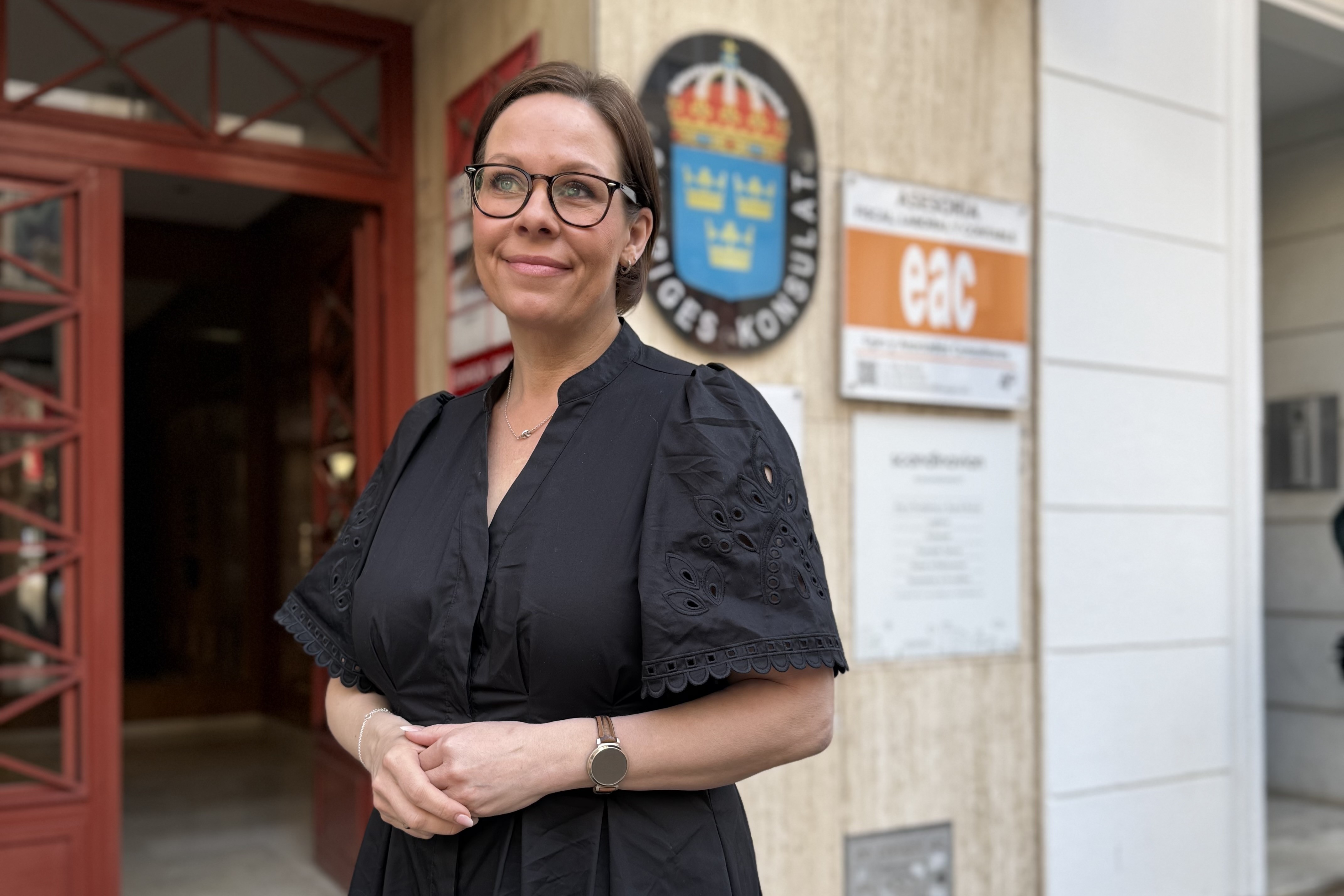 Utrikesministern står utomhus framför Sveriges konsulat i Torrevieja.