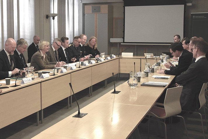 Foto på personer som sitter runt ett konferensbord.