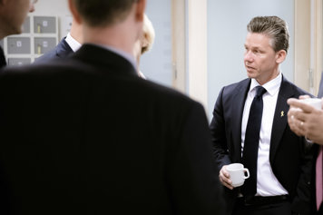 Foto på försvarsminister Pål Jonson som står och pratar med en person som man ser ryggen på.