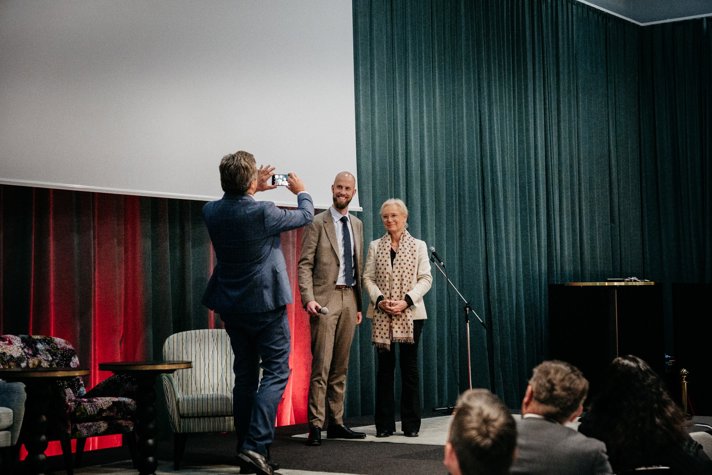Minister för civilt försvar Carl-Oskar Bohlin och MSB:s generaldirektör Charlotte Petri Gornitzka står på scen och blir fotograferade av en man med mobilkamera.