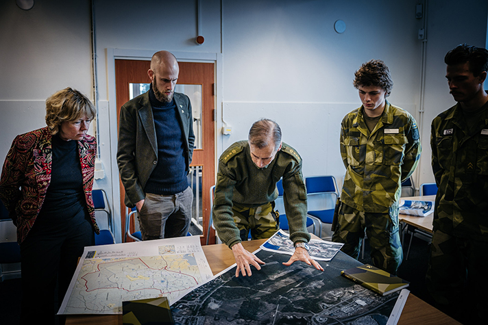 Landshövding Helena Höij, Carl-Oskar Bohlin, regementschef Ronny Modigs och värnpliktiga samtalade om civil och militär samverkan vid ett bord med kartor