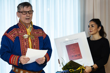 Kulturminister Parisa Liljestrand  håller i diplom och blommor till pristagaren Ole Henrik Magga som håller tal