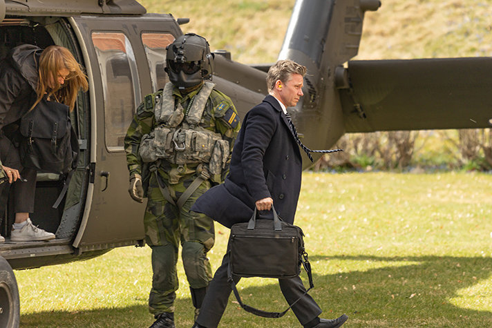 Pål Jonson har nyss klivit ur helikoptern och går bort ifrån den. Vinden yr och Påls slips står rakt ut. En besättningsmedlem står vid sidan av helikoptern redo att hjälpa till de som kliver ur.