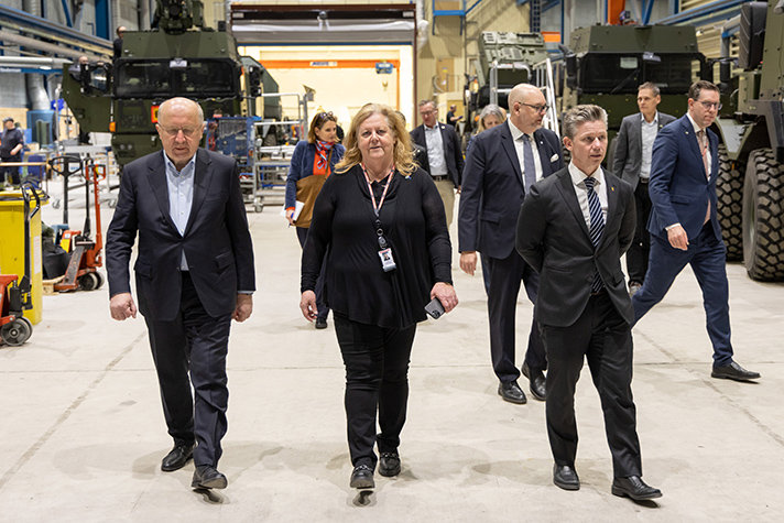 Kubilius, Lena Gillström och Pål Jonson går inne i en monteringshall hos BAE Bofors. I bakgrunden ses montering av artillerisystemet Archer.