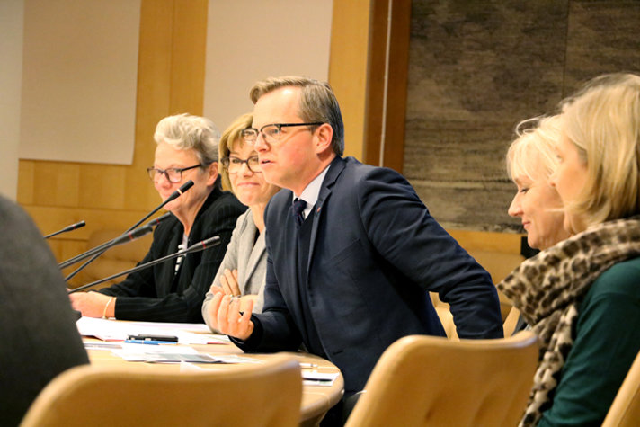 Flera personer sitter vid ett konferensbord. Närings- och innovationsminister Mikael Damberg talar i mikrofonen.