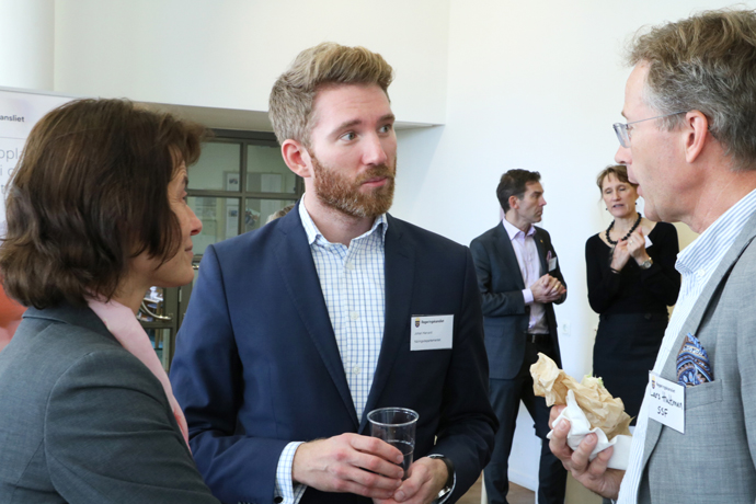 Tre personer står och samtalar med varandra.