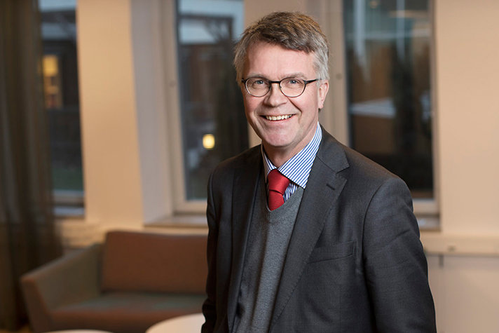 Peter Larsson, regeringens samordnare för samhällsomställning vid större företagsetableringar och företagsexpansioner i Norrbotten och Västerbotten står i ett större rum framför en soffa för att bli fotograferad.