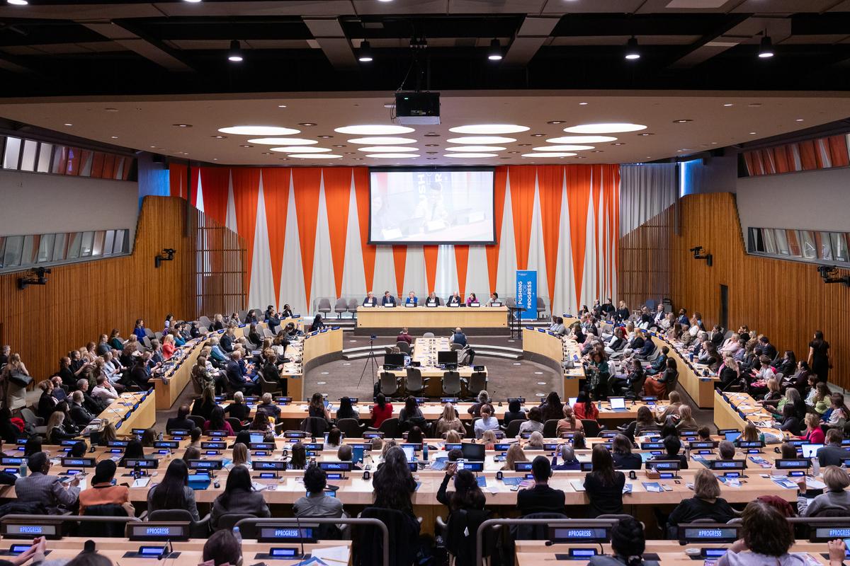 Ett stort rum med flera åhörare. Några personer sitter längst fram i en panel.