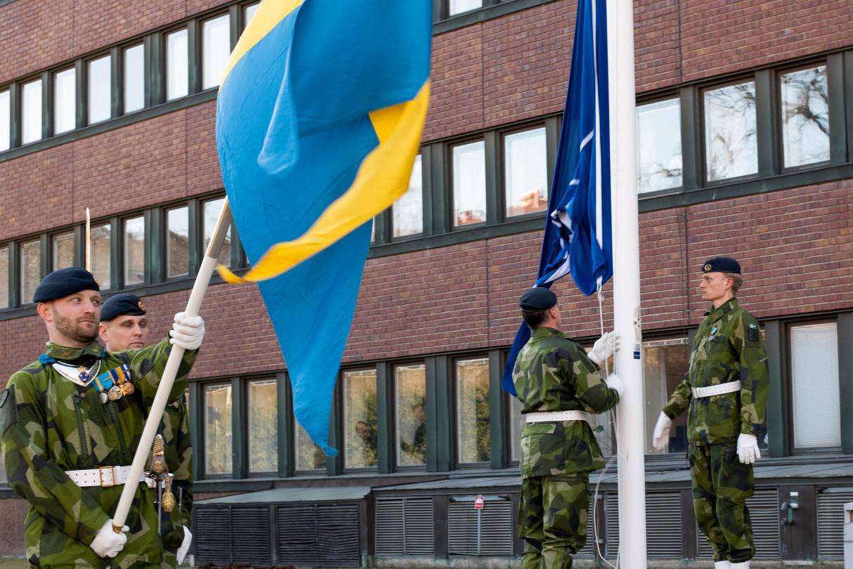 Soldater hissar en Sverigeflagga och en Natoflagga.
