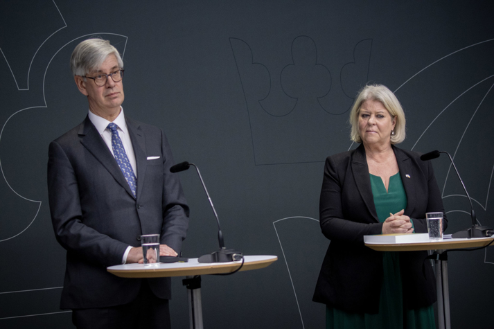 Anders Hagsgård och Camilla Waltersson Grönvall står bakom varsitt ståbord i regeringens pressrum och talar till publiken.