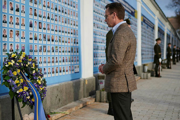 Statsminister Ulf Kristersson framför en blomsterkarans vid en minnesmur för stupade soldater i Kiev.
