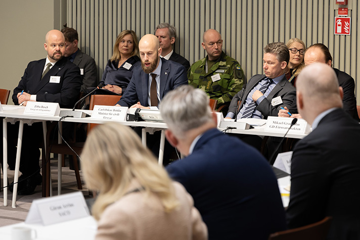 Carl-Oskar Bohlin inleder mötet sittandes bakom ett bord. T.v. om Bohlin sitter Pål Jonson