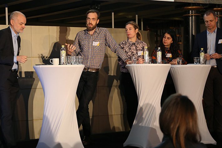 Moderator Lasse Truedsson står på scen vid talarstolarna och talar med panelen som är Gustav Martner, Karin Pettersson, Rosaline Marbinah och Henrik Selin.