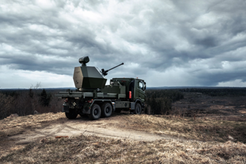 Luftvärnskanon av typen Tridon Mk 2 placerad på en kulle med utsikt över granskog.
