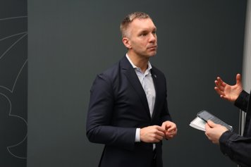 Civilminister Erik Slottner blir intervjuad av journalist framför grå bakgrund.