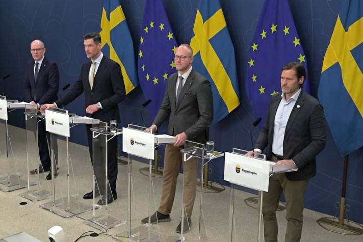 De fyra medverkande står bakom var sin talarstol. Det är flaggor i fonden.