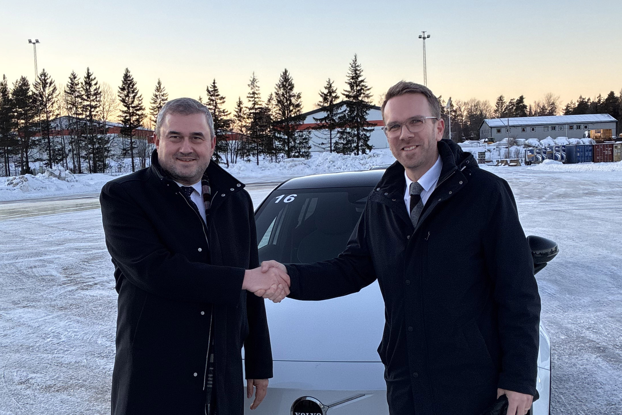 Andreas Carlson skakar hand med en man som representerar Polens regering framför en bil i ett vintrigt landskap