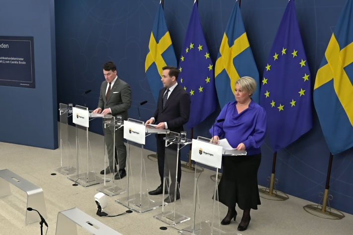 Tre personer avbildade snett uppifrån står vid var sin talarpulpet.r vid va