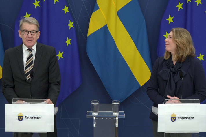 Två personer står vid var sin talarpulpet.