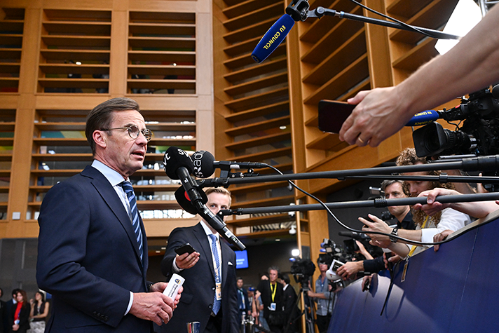 Ulf Kristersson står framför flera mikrofoner som sträcks fram av journalister.