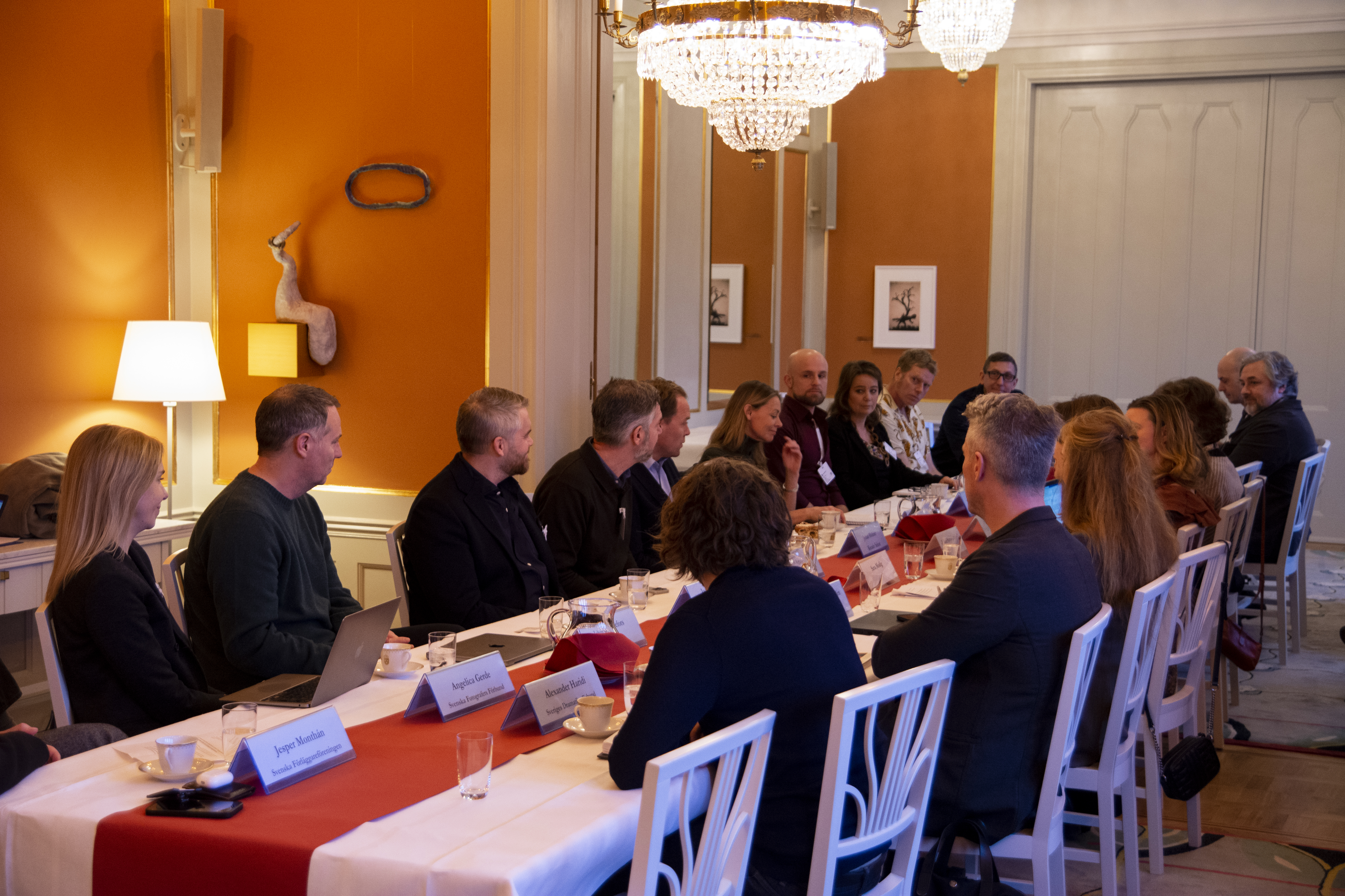 Ett tjugotal personer sitter runt ett bord och samtalar