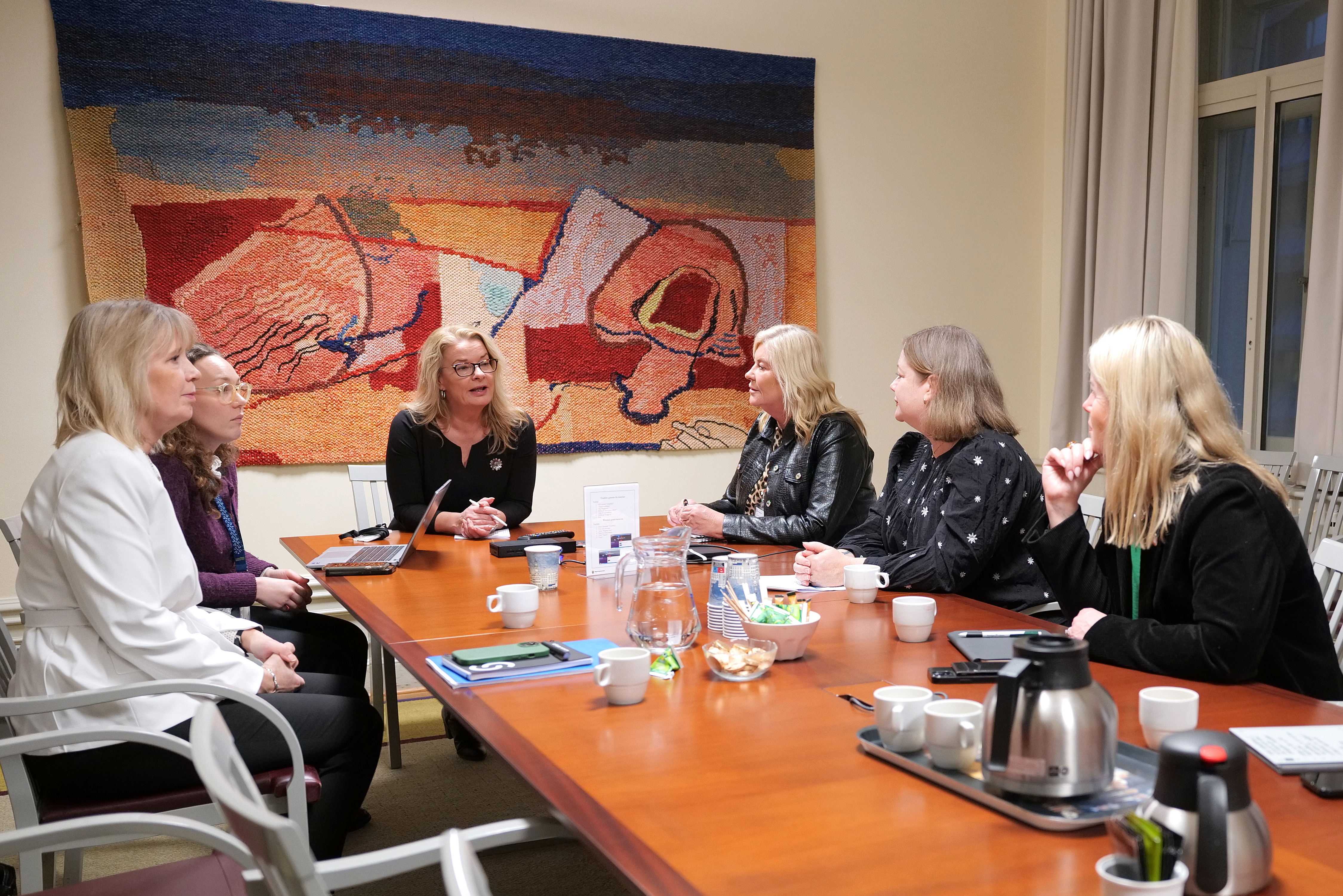 Skolministern vid bord i samtal med representanterna.