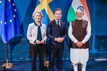 De tre medverkande står framför va sin flagga, EU-flaggan, Sveriges flagga och Indiens flagga.