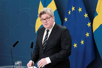 justitieminister Gunnar Strömmer står vid en talarpulpet. Flaggor i fonden.