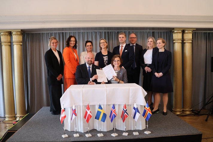 Två personer sitter vid ett bord med deklarationen. De övriga står bakom.