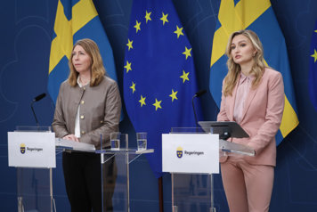 Elisabet Lann och Ebba Busch står och talar vid varsin talarstol i regeringens pressrum. Bakom dem syns den svenska och EU-flaggan.