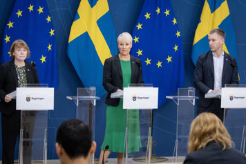 Danielsson, Tenje och Slottner står bakom varsin talarstol rí regeringens pressrum, framför svenska och EU-flaggor.