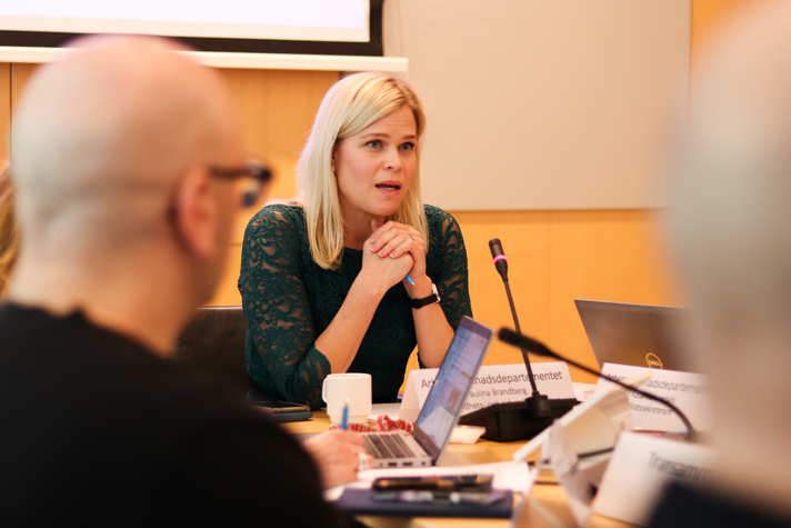 Paulina Brandberg, jämställdhets- och arbetslivsminister, sitter vid ett bord. På bilden syns ytterligare personer.