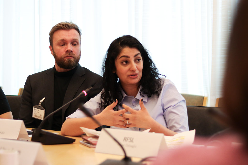 Några personer sitter vid ett bord och pratar i samband med ett möte.