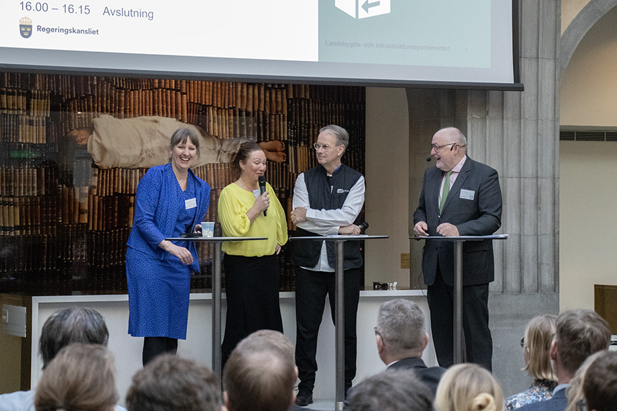 Fyra personer står på en scen och pratar framför en publik