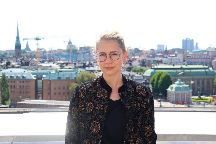Freja står på en takterrass. I bakgrunden syns Stockholm.
