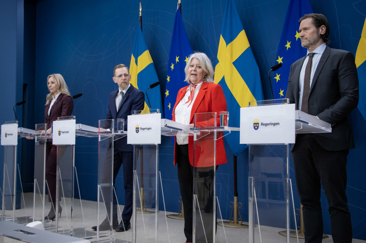 Deltagande statsråd och talespersoner står bakom varsin talarstol i regeringens pressrum